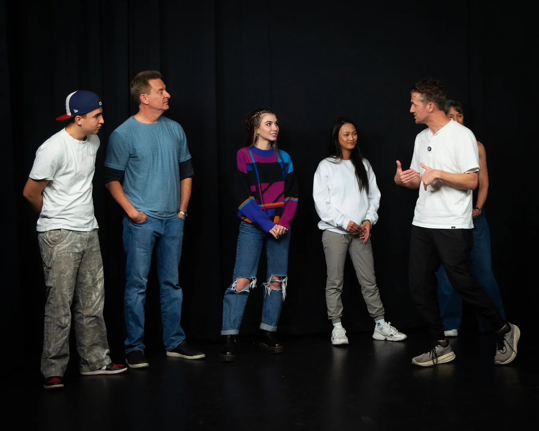 Matthew Dearing giving notes to a line of actors on the black stage at callbacks