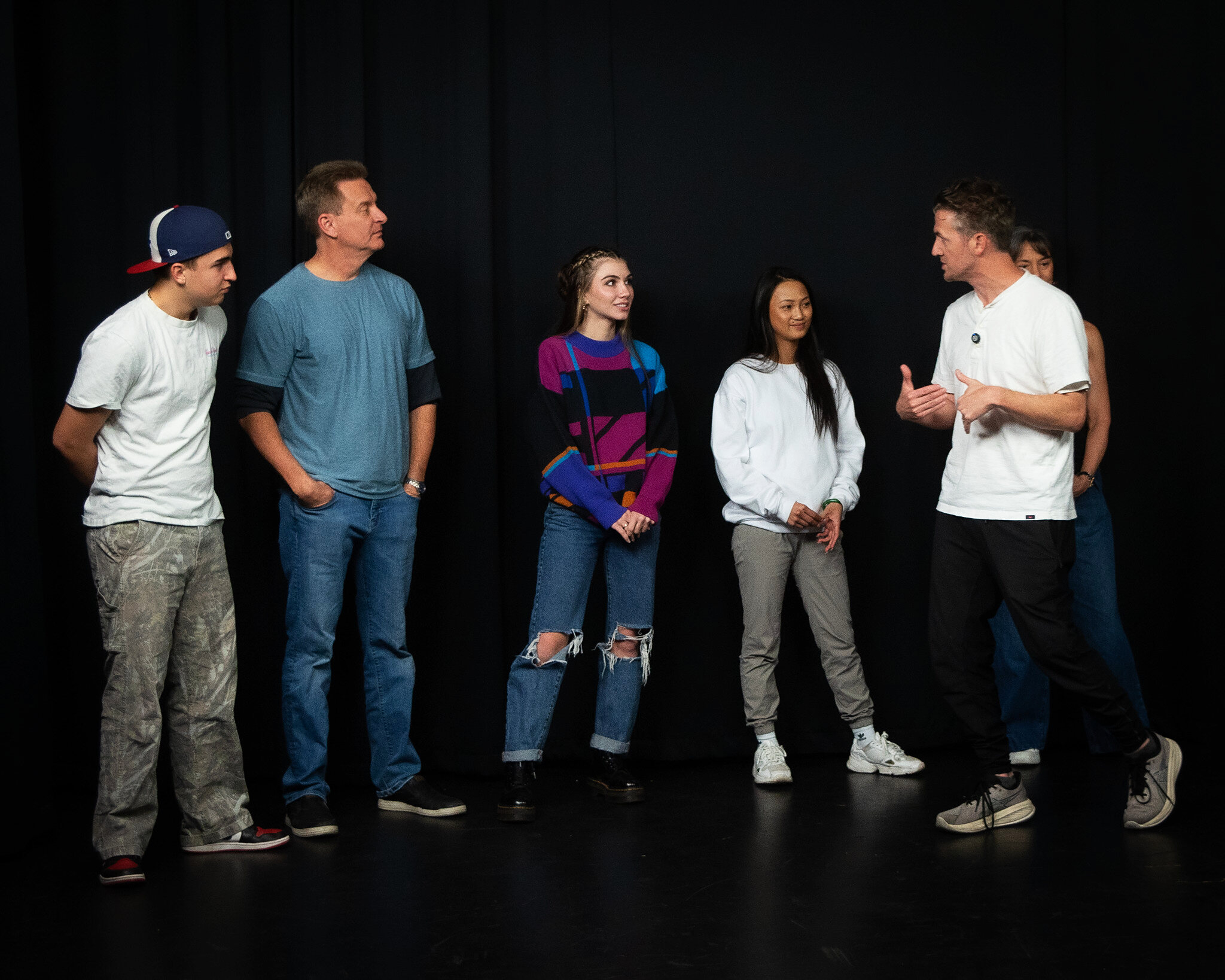Matthew Dearing giving notes to a line of actors on the black stage at callbacks